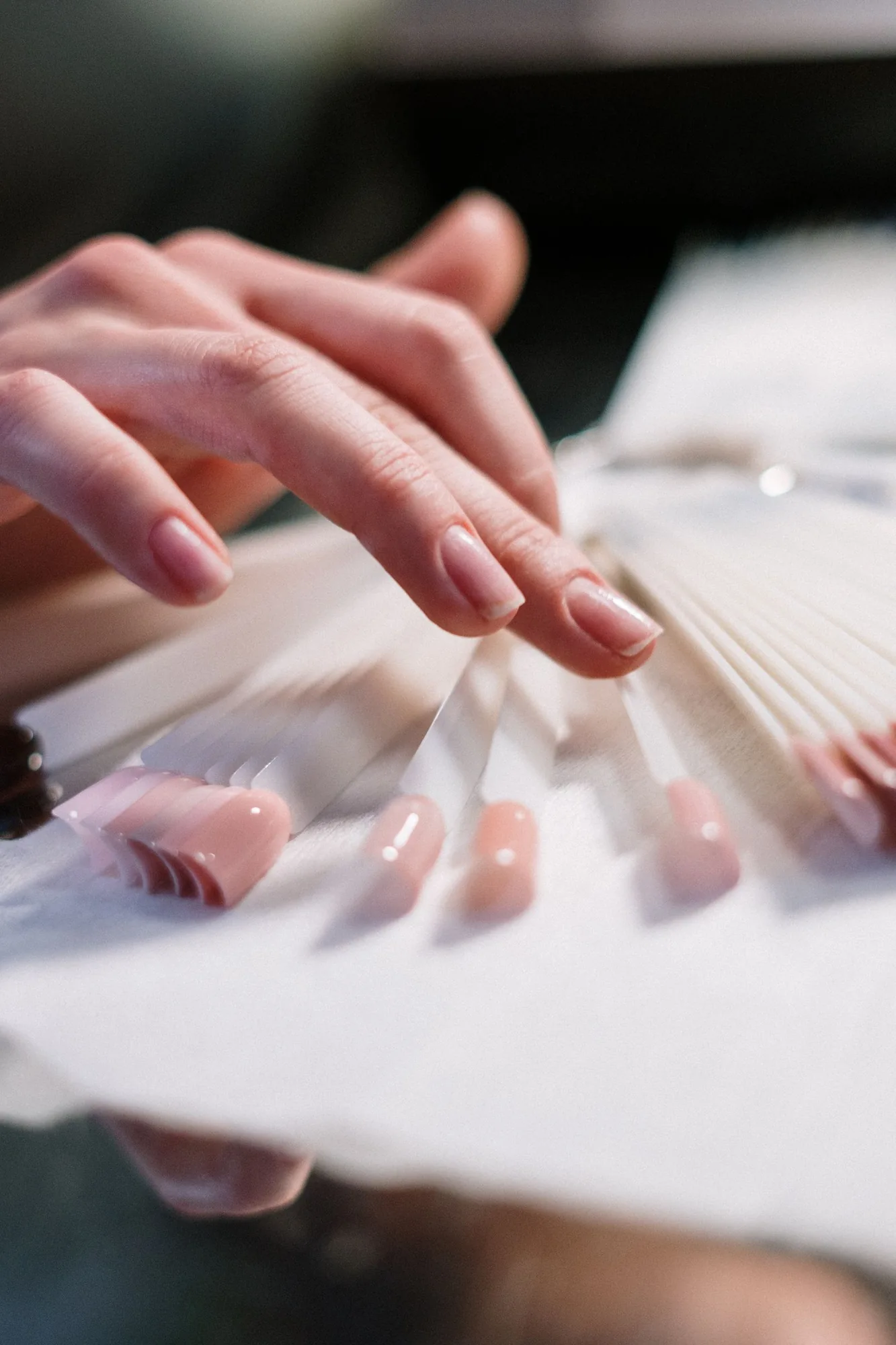 A hand choosing from a fan of nail colour samples