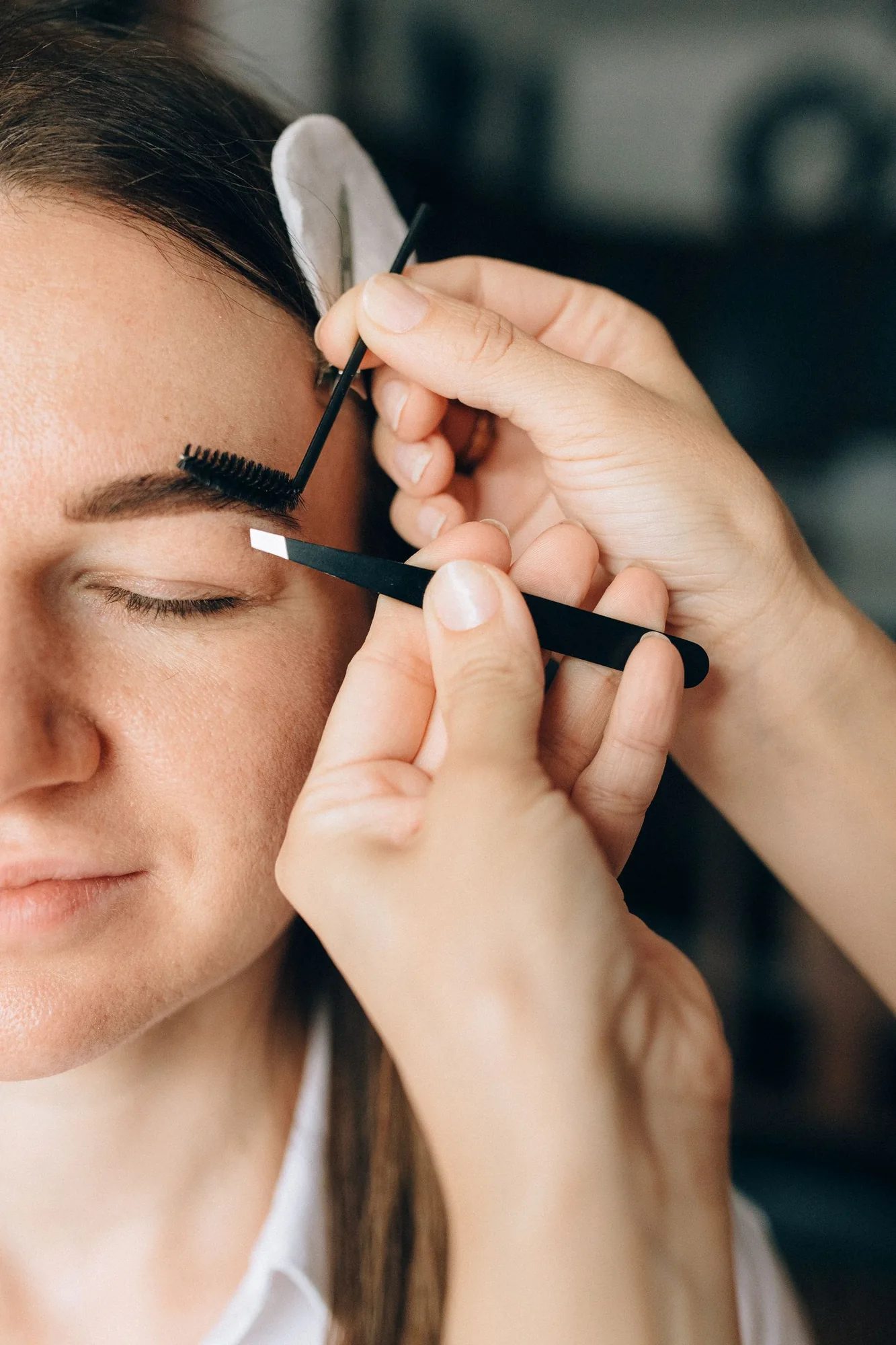 Close-up of careful eyebrow shaping with tweezers