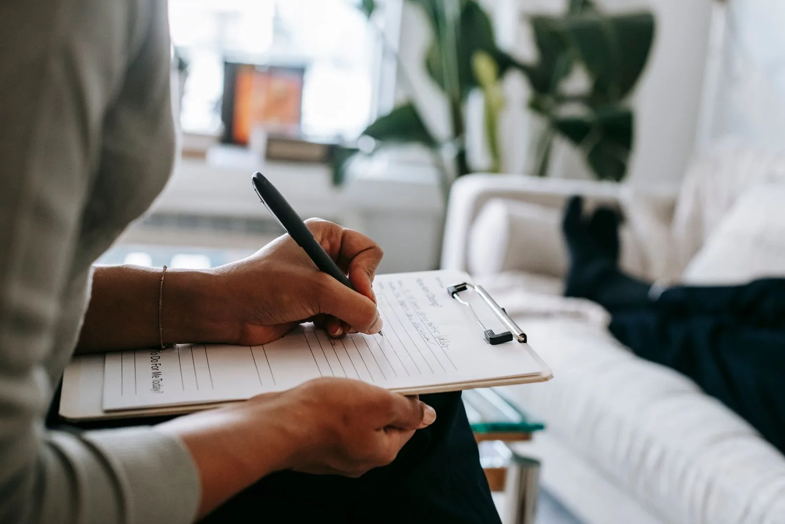 Hands taking notes on a clipboard during a conversation