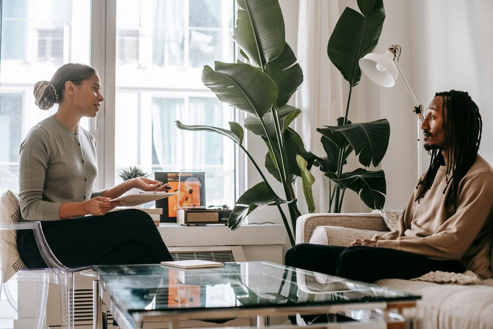 Two people seated in conversation beside a bright window