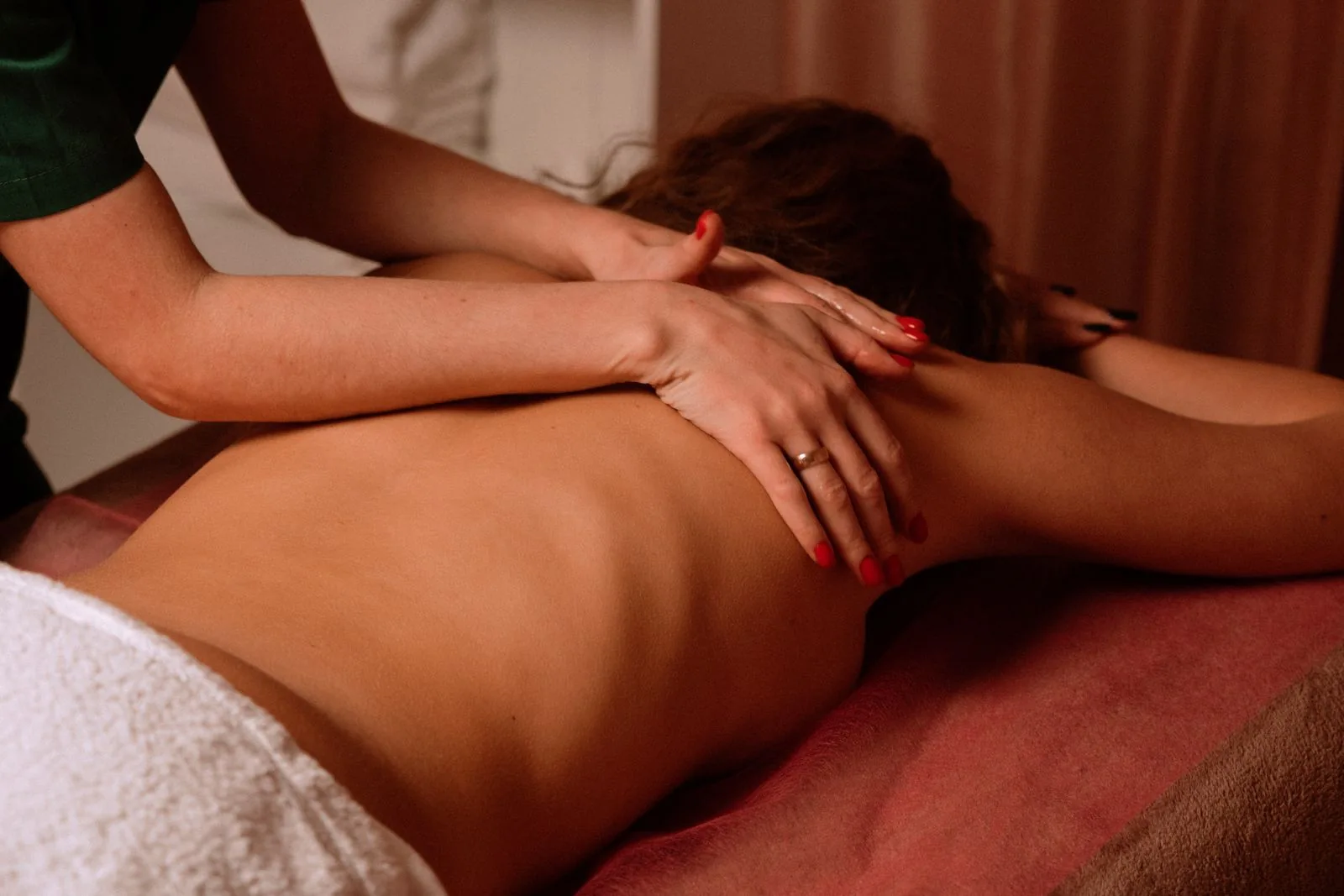 Hands massaging the shoulders and upper back on a treatment table