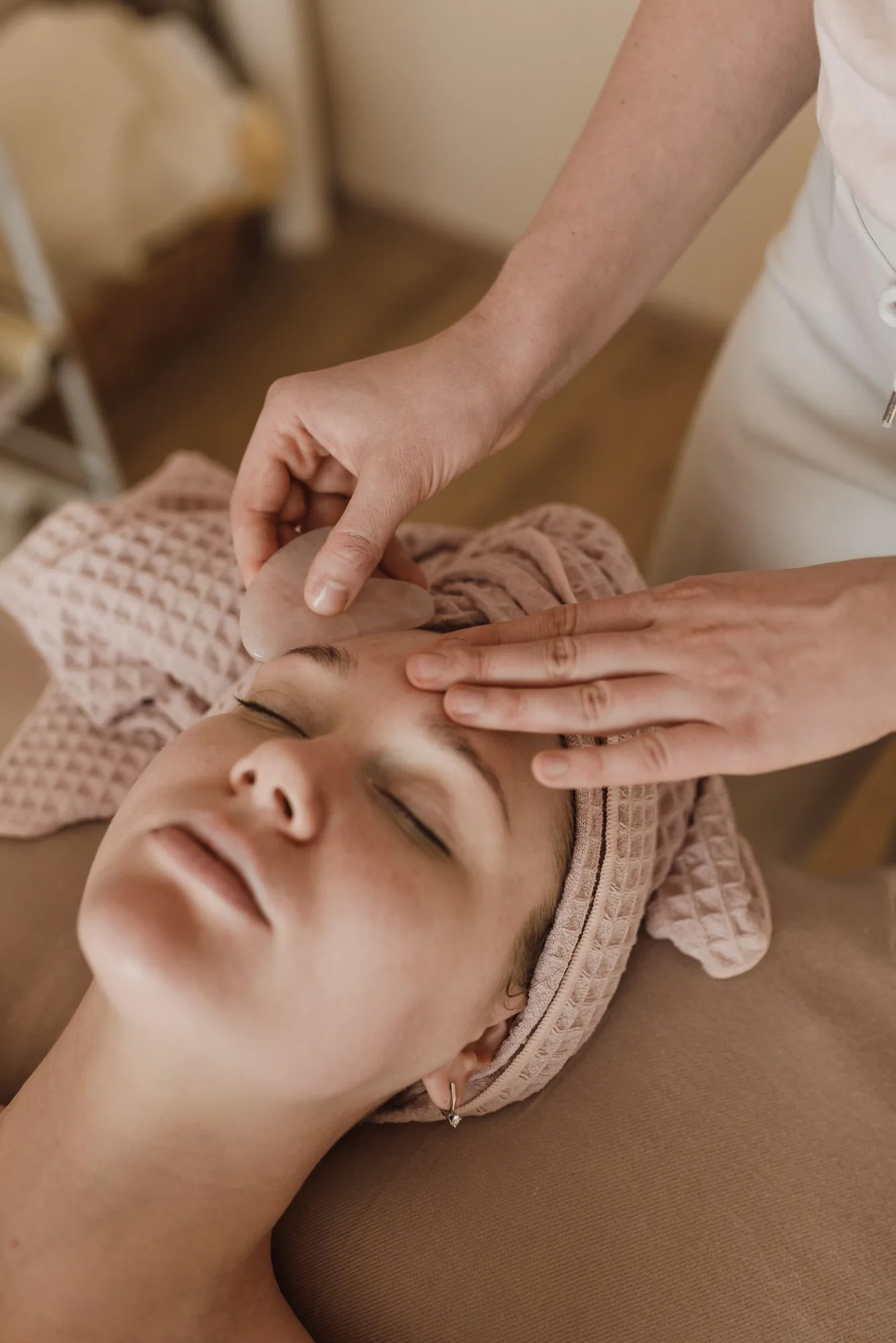 A facial massage with a smooth stone tool and a soft head towel