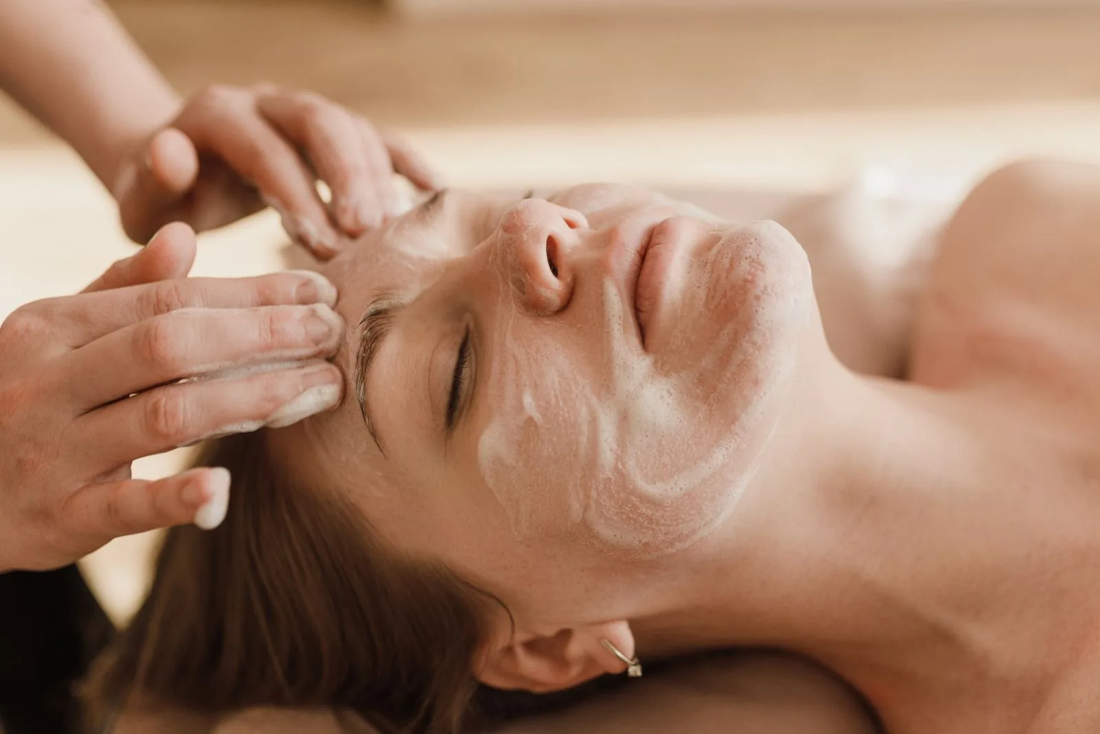 Hands gently applying cleanser during a facial treatment